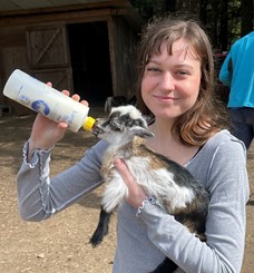 Female holding and bottle feeding a baby goat